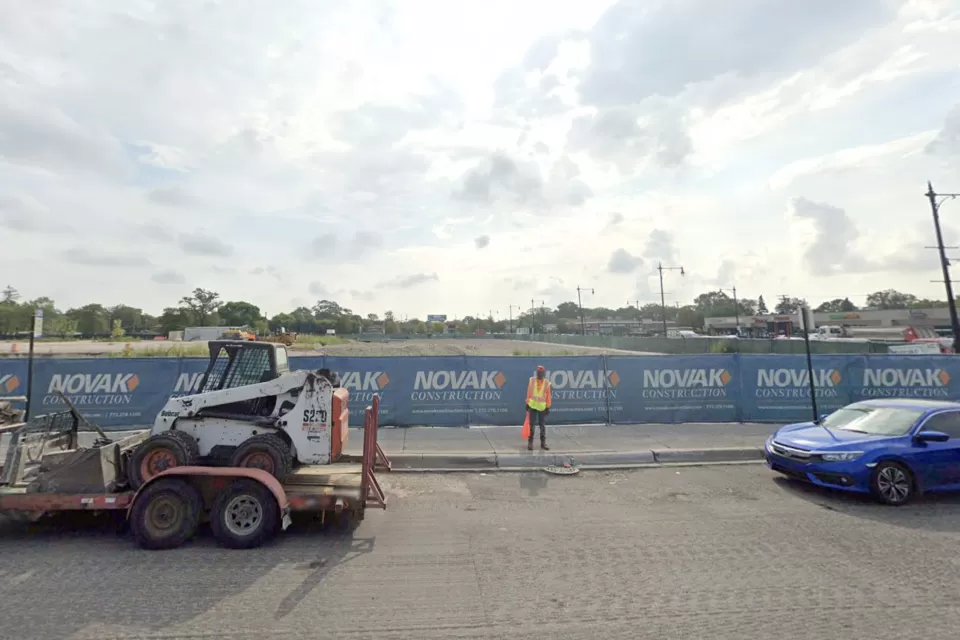 Google Street View of empty construction site with blue construction fence